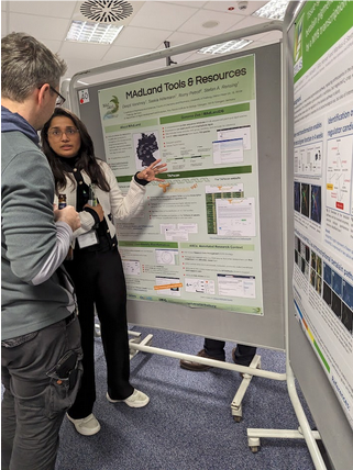 Deepti Varshney presenting the MAdLand poster at the MBP2024 conference. She is in conversation with one of the conference attendees